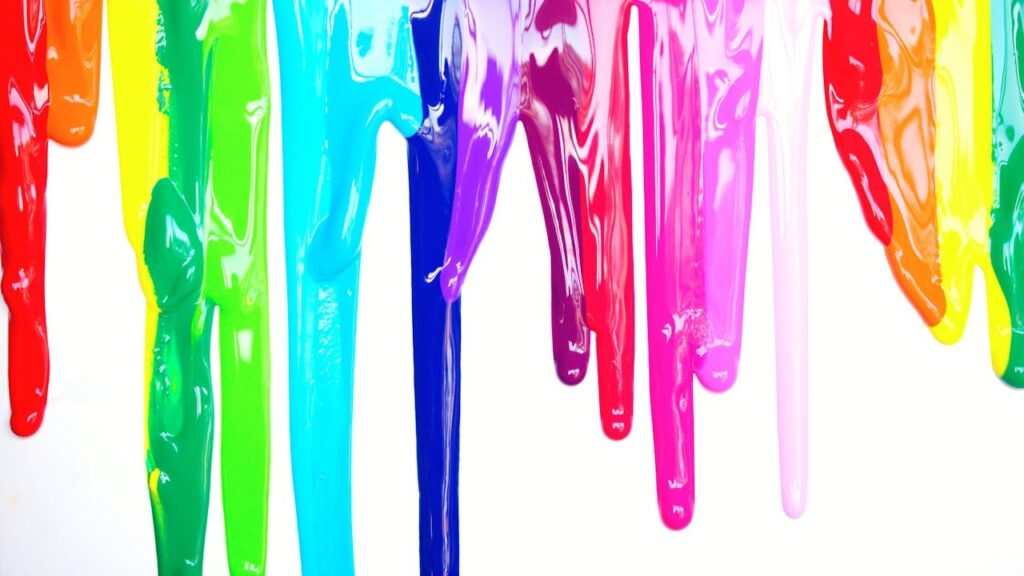 Druipende verfresten in felle kleuren op een witte muur, symbool voor verfresten verwijderen