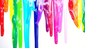 Druipende verfresten in felle kleuren op een witte muur, symbool voor verfresten verwijderen