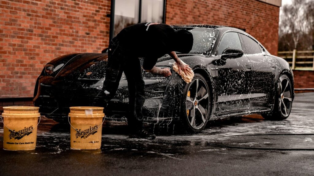 Man wast een zwarte sportauto met spons en twee emmers volgens de handwasmethode – auto wassen