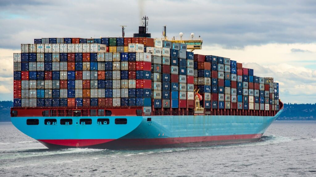 Containerschip volgestapeld met kleurrijke containers vaart op zee – focus op scheepsreiniging essentieel.