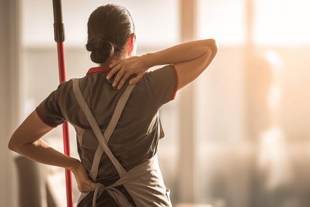 Schoonmaker doet rekoefeningen tijdens een korte pauze om het lichaam soepel te houden na het schoonmaken.