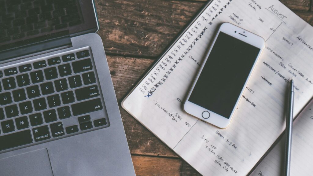 Onderhoudsplan bijhouden met laptop, agenda en smartphone op houten bureau