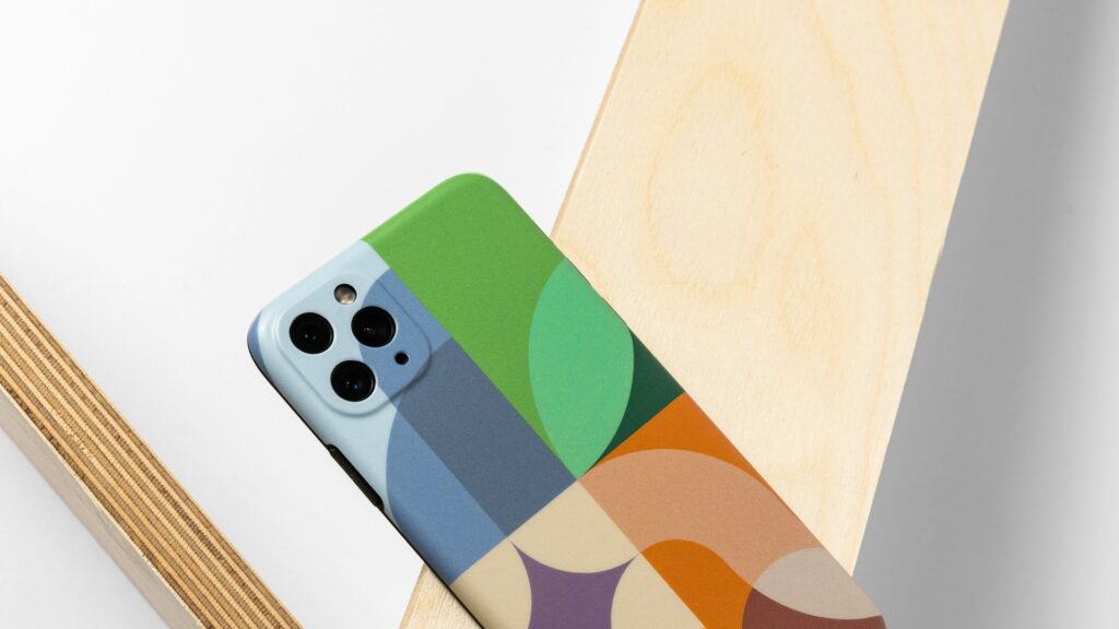 Smartphone met kleurrijk, geometrisch telefoonhoesje leunend tegen een houten oppervlak – smartphonehoesje schoonmaken
