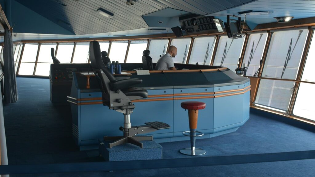 Moderne brug van een schip met stuurinrichting en bemanningslid – centrale rol bij veilige scheepsreiniging.