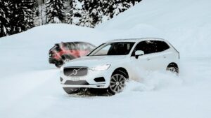 Witte SUV rijdt door verse sneeuw in bosrijke omgeving – aandacht voor condens op glas en winterveiligheid.