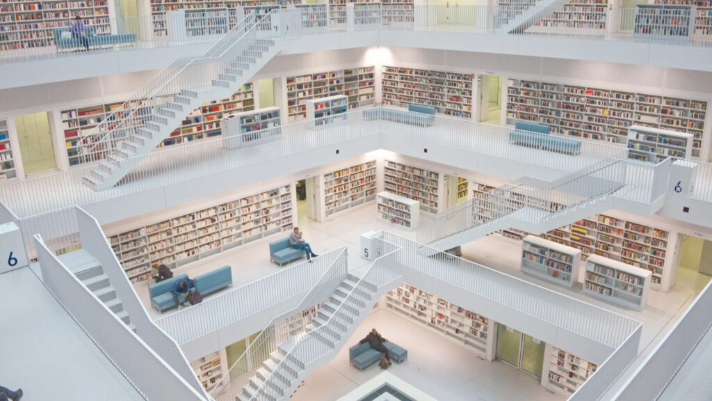 Grote, lichte bibliotheek met gestructureerde boekenkasten en rustige zithoeken straalt orde en netheid uit.